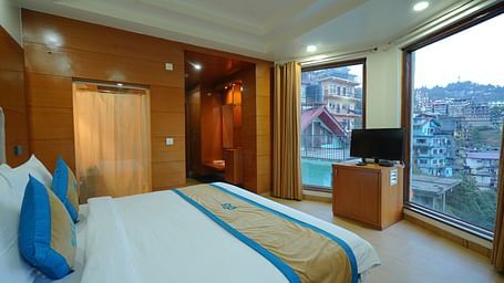 A bedroom  showcasing the view through glass windows and a TV on a table at DLS Hotels The Rock Castle.